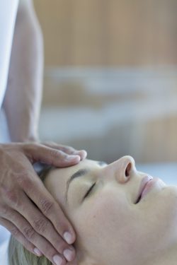 Serene young woman receiving head massage in spa